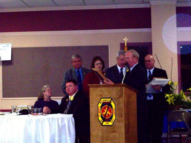 County Commissioner President Russell reads one of the plaques that were given to the department to hang at each station